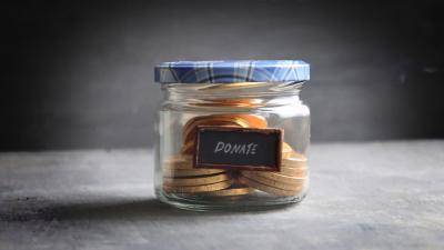 Small jam jar, labeled "donate" filled with gold coins.