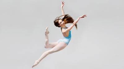 graceful dancer in blue leotard in mid-air jump
