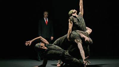 Michael Tusnovec in a business suit and other dancers wearing army uniforms in Paul Taylor's "Banquet of Vulture"