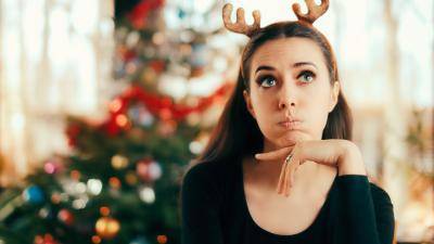 young woman bored in front of a Christmas tree