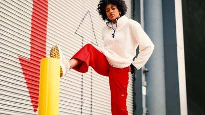 Black woman in red sports pants in front of a roller door with 2 arrows pointing up and down
