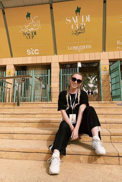 Dancer Charlie Kingston sitting on stairs in front of Saudi Cup event