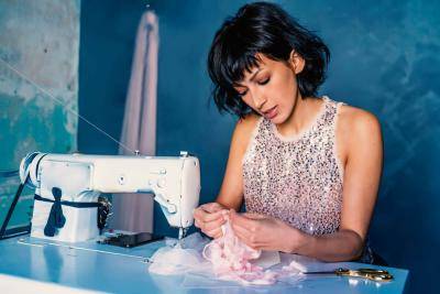 young woman in a sequins top at a sewing machine