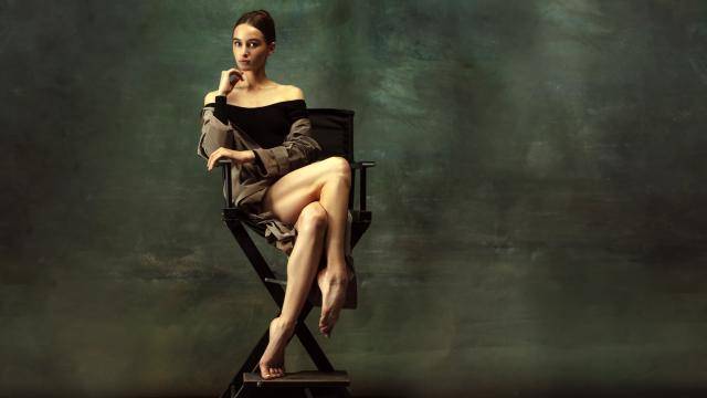 ballerina gracefully sitting legs crossed on a director's chair