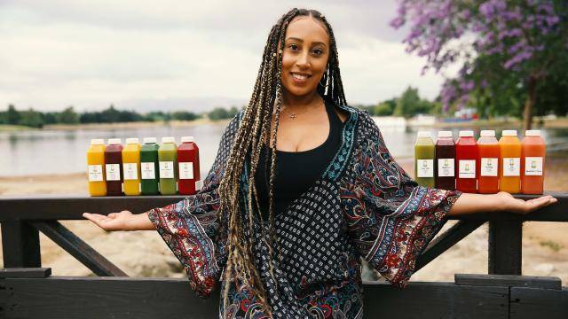 Aleksia Hill and a row of Snatched Juice bottles on a beach background