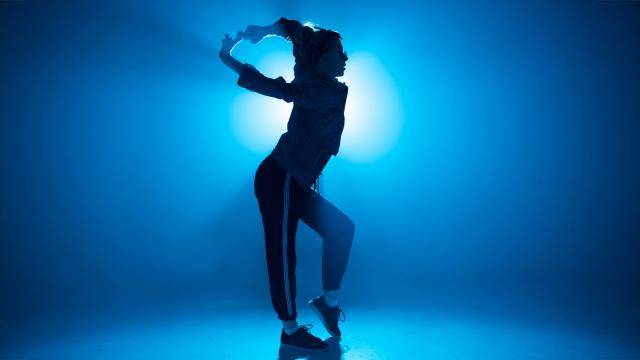 Silhouette of a breakdancer posing in front of a blue lit background