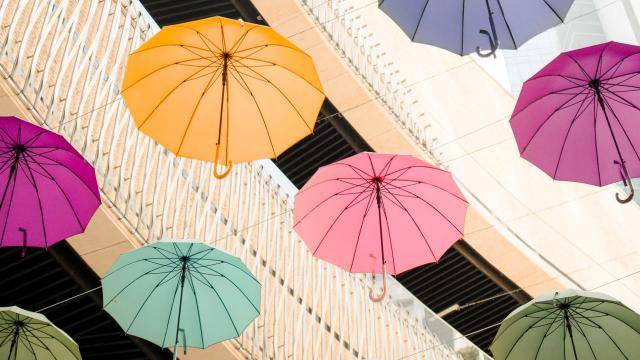 colorful umbrellas floating in the air against a building background